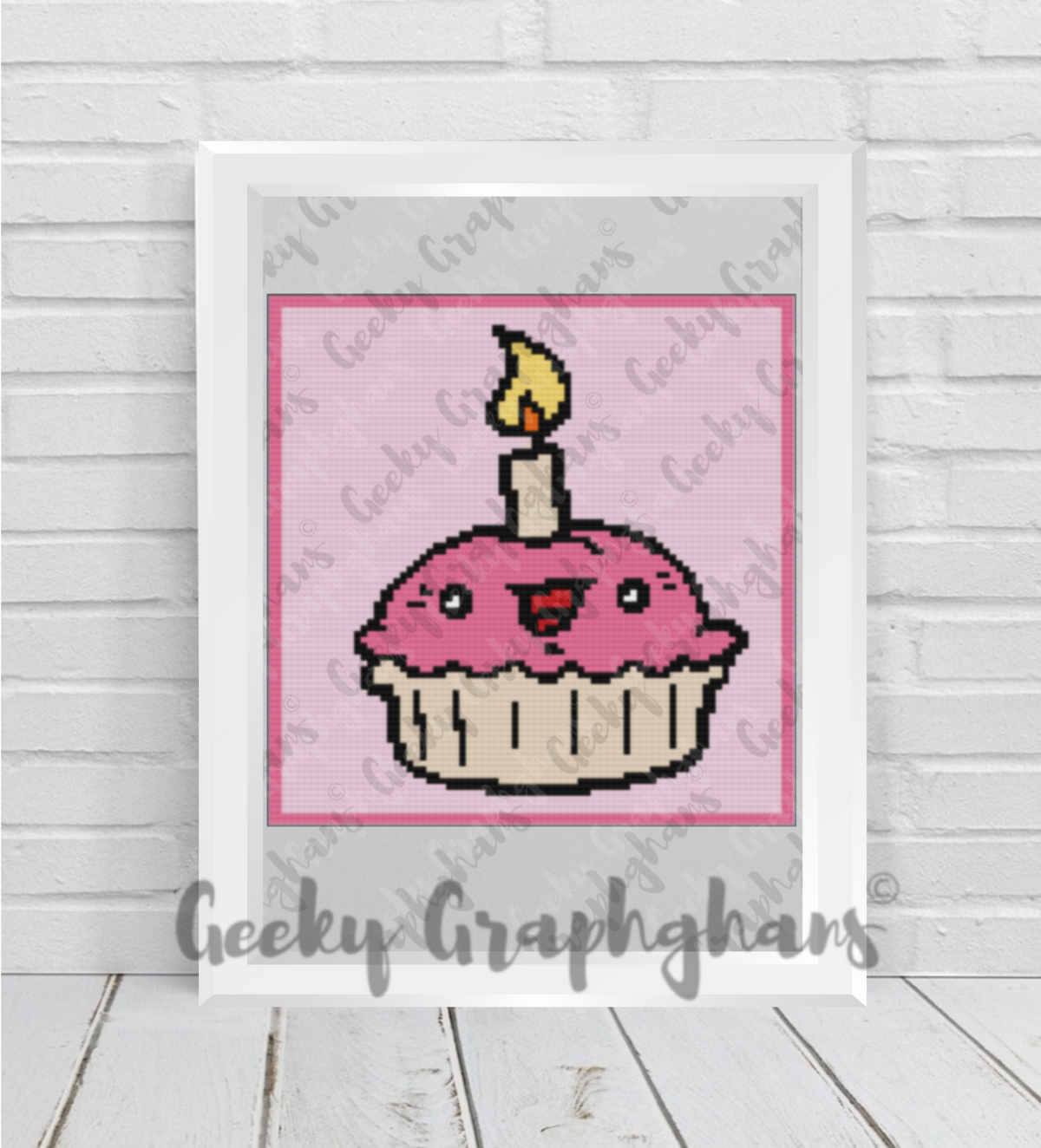 Crochet design of a pink cupcake with a candle on a white background, framed by 'Geeky Graphghans'.