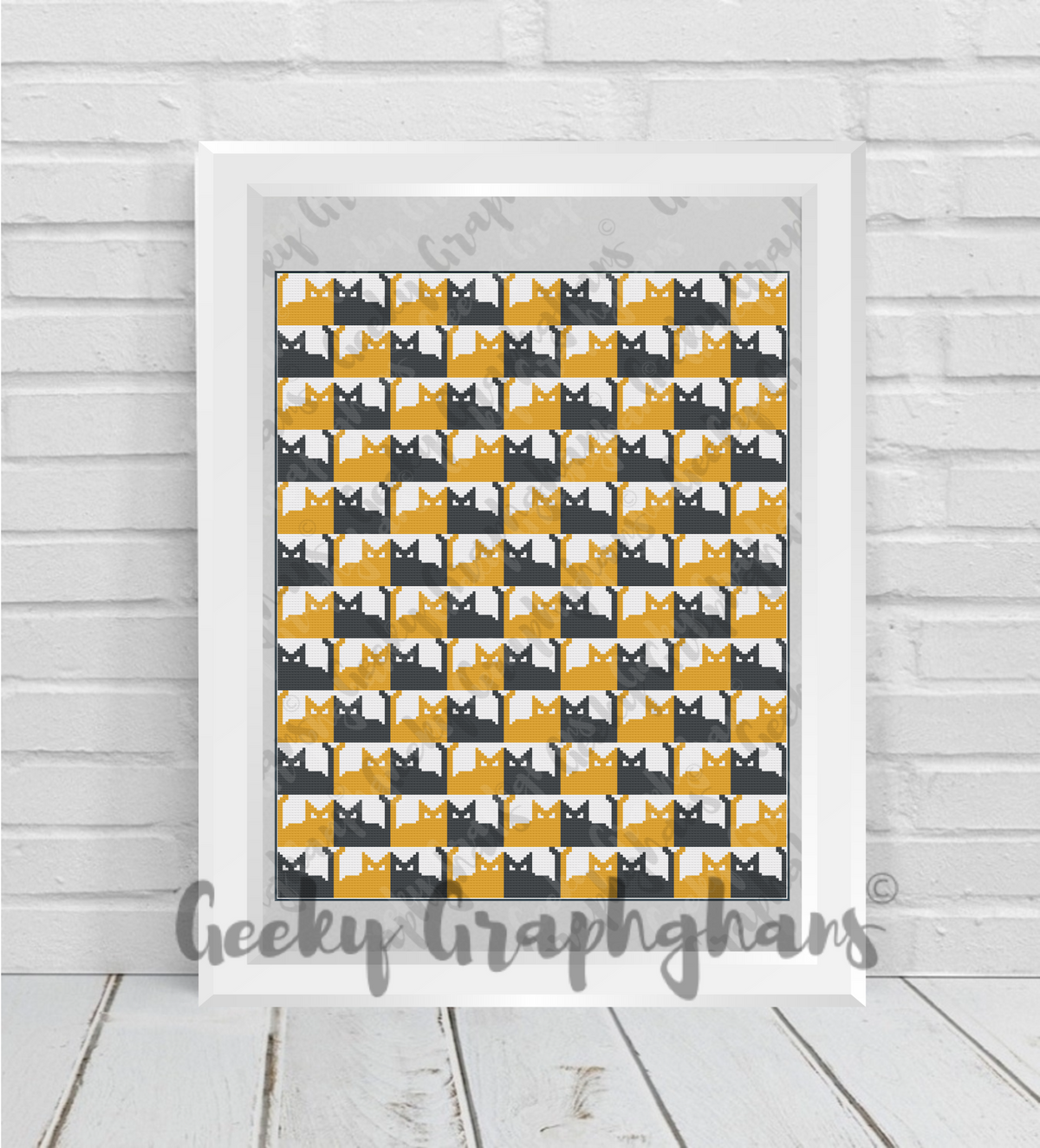 Framed artwork with a pattern of black and yellow cats on a white wall. Crochet Graphghan pattern by Geeky Graphghans