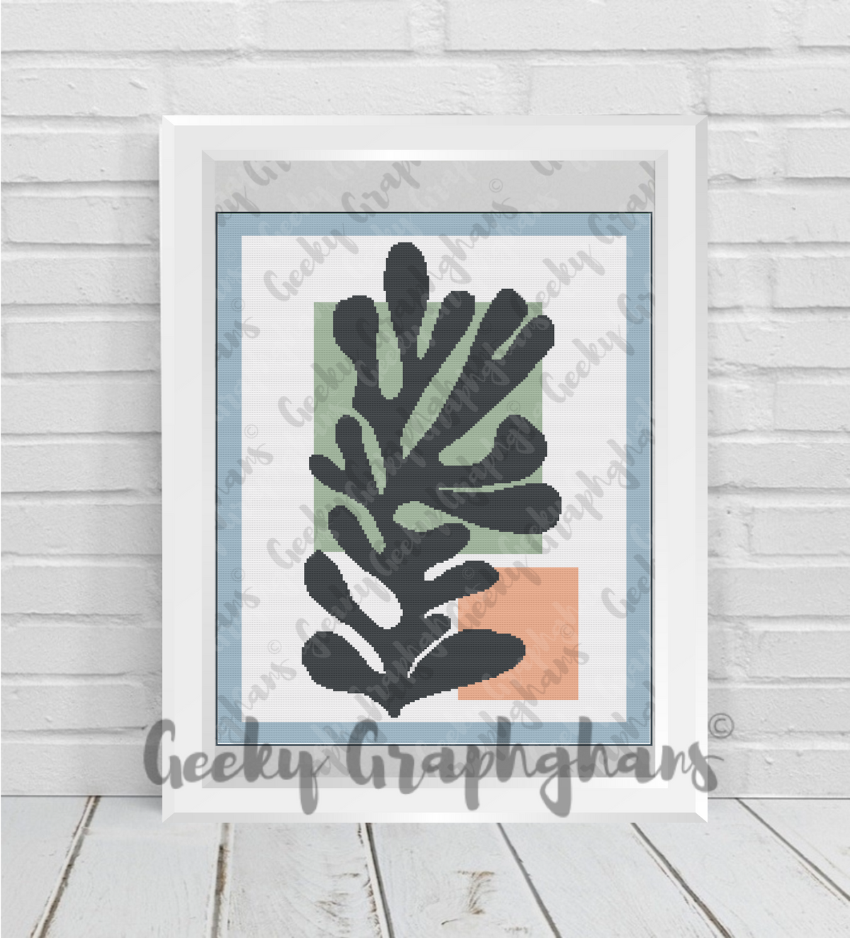 Framed artwork with black leaf design on a light gray background, branded 'Geeky Grapghans'. Crochet Graphghan pattern by Geeky Graphghans