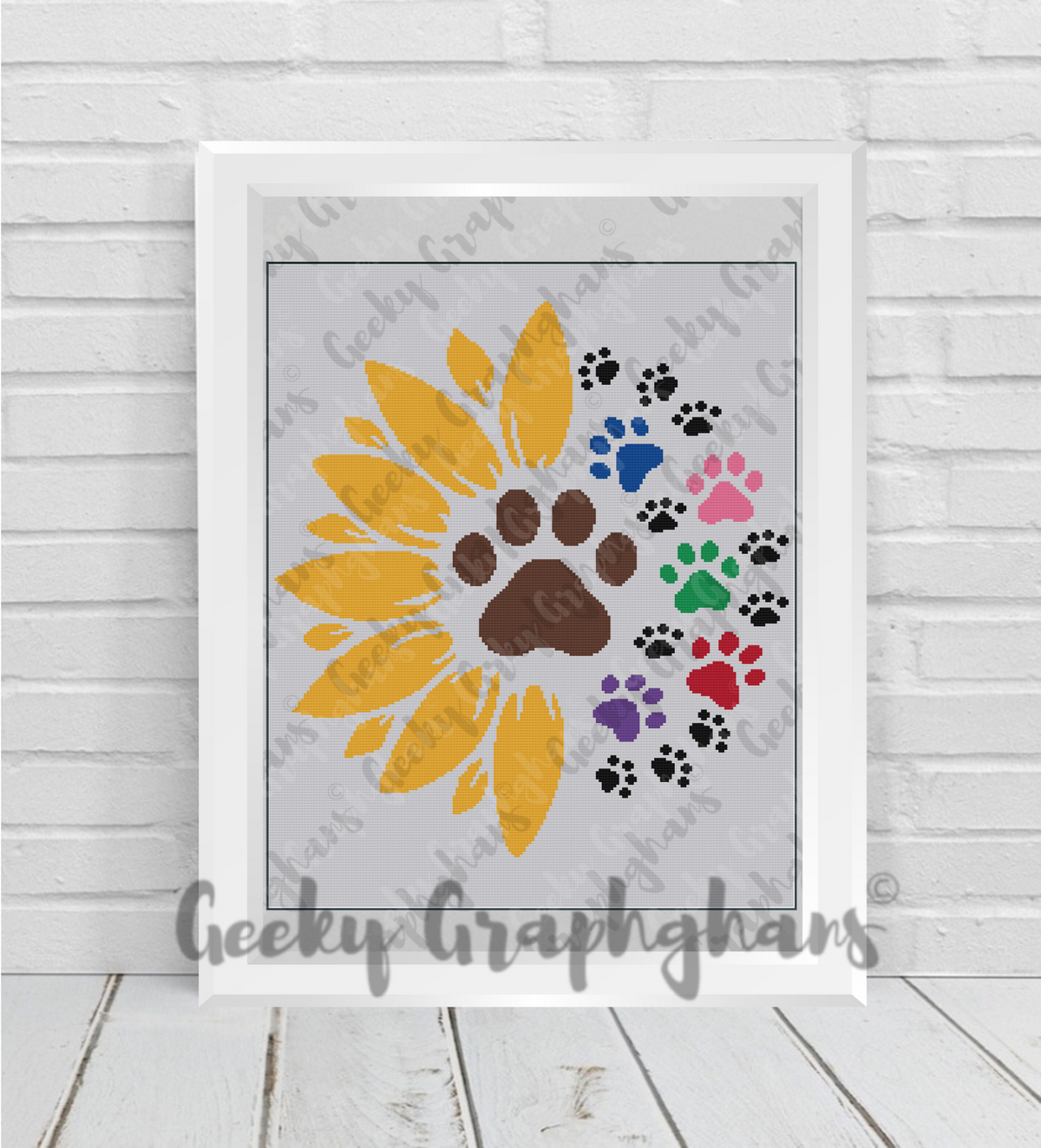 Framed artwork with a yellow sunflower design and colorful paw prints on a light wooden floor. Sunflower paws crochet graphghan pattern