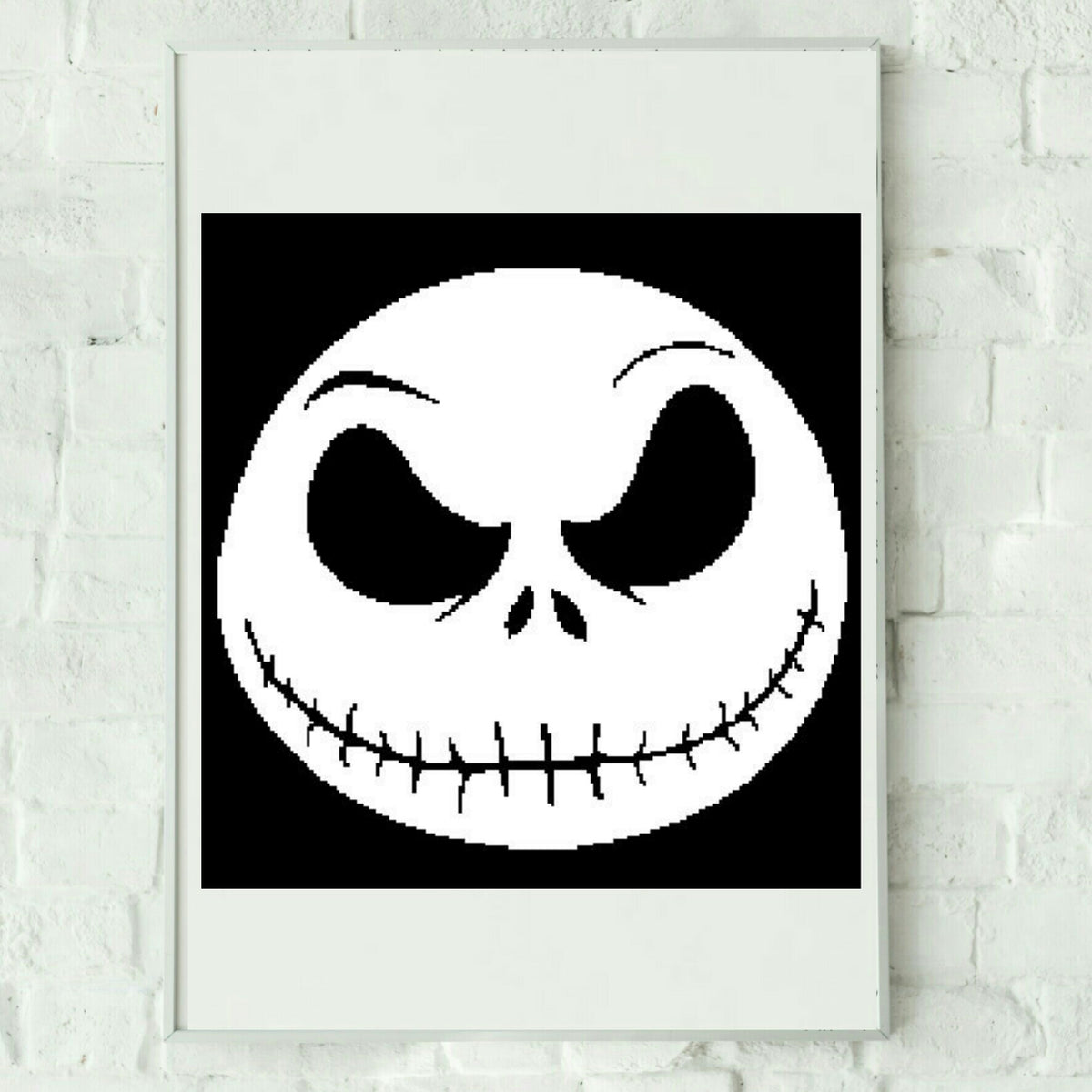 A graphic image of Jack Skellington's grinning skull with black hair and white bones, primarily in black and white colors, displayed on a white background, intended to be crocheted or knitted.