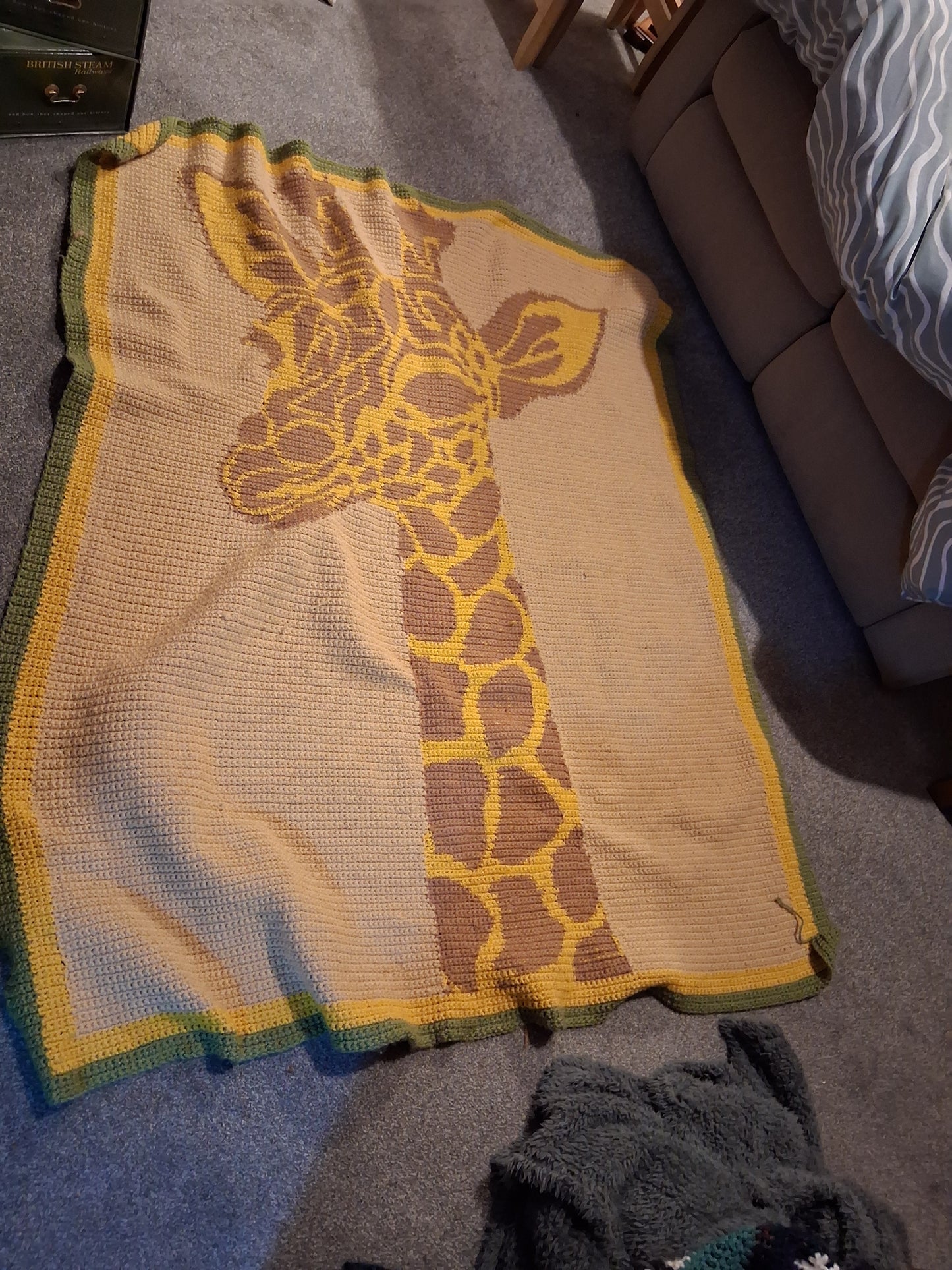 Giraffe-patterned blanket on a couch. Crochet graphghan crocheted by Carolyn Fitzpatrick
