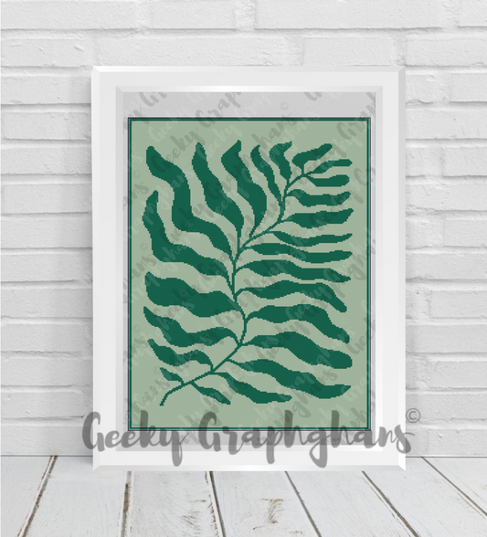 Framed artwork with a green leaf design on a light green background, displayed on a wooden floor.