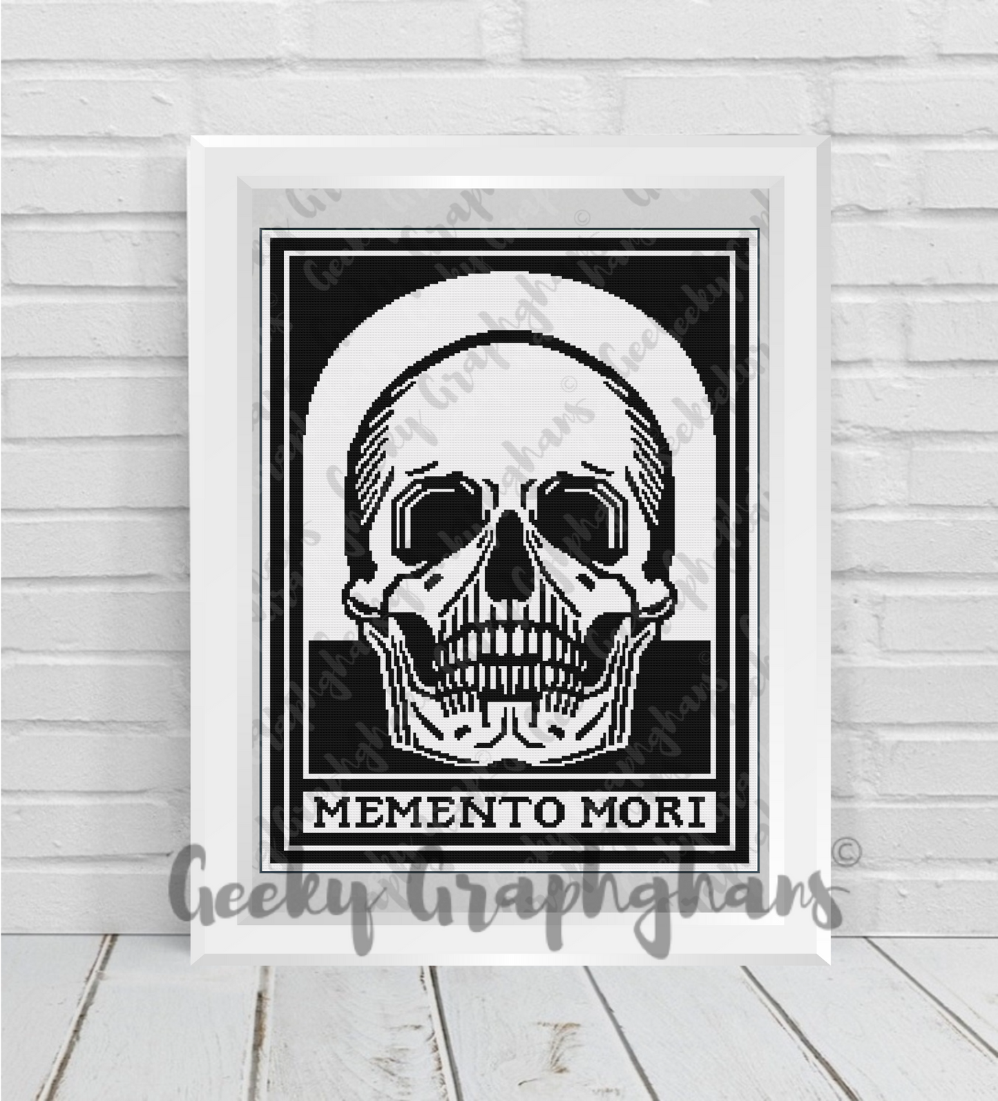 Framed artwork of a skull with 'Memento Mori' text on a white brick wall. Crochet Graphghan pattern by Geeky Graphghans