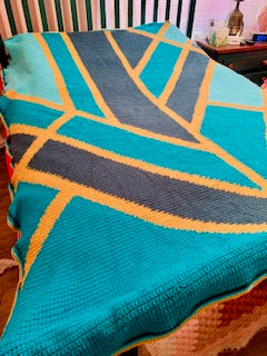 Textured blanket with geometric pattern on a surface. Art Deco crochet graphghan pattern by Geeky Graphghans. Crocheted by Norma Hodge