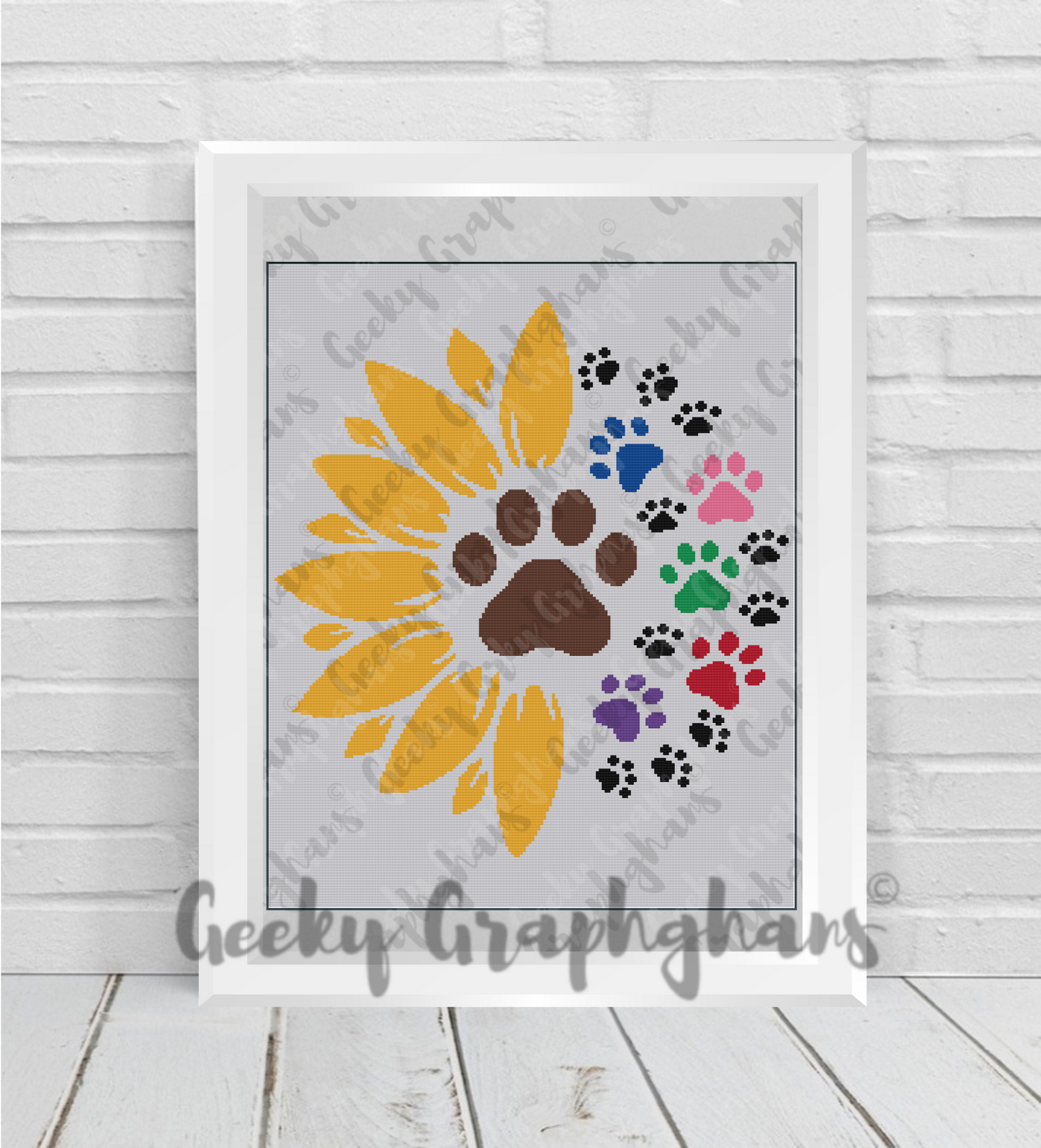 Framed artwork with a yellow sunflower design and colorful paw prints on a light wooden floor. Sunflower paws crochet graphghan pattern