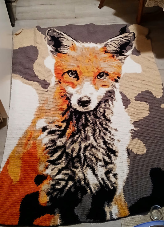 Rug with a fox design on a wooden floor. Crochet graphghan fox blanket crocheted by Tammy Sandrock. Design by Geeky Graphghans