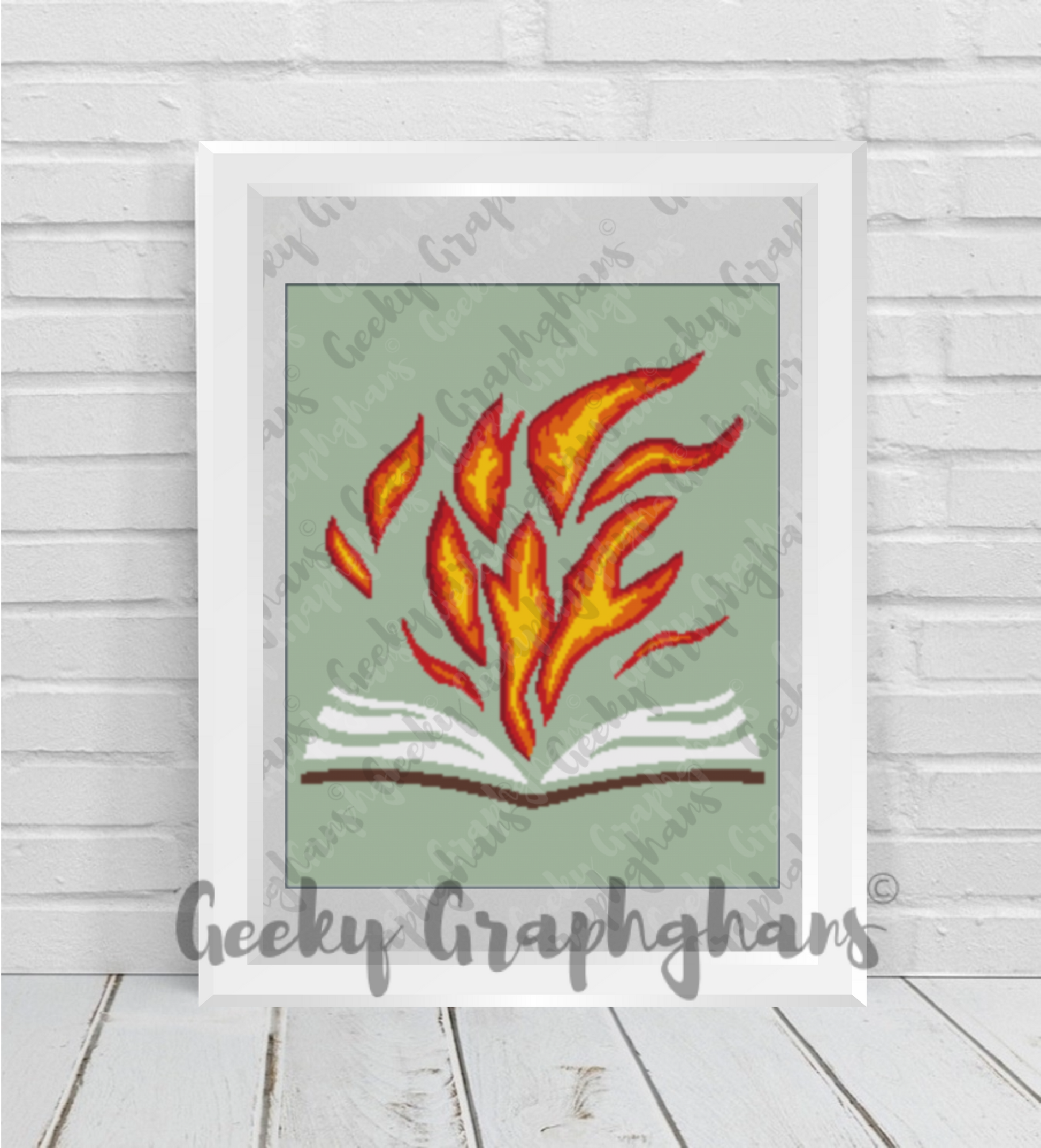 Framed artwork of flames emerging from an open book on a light wooden floor.